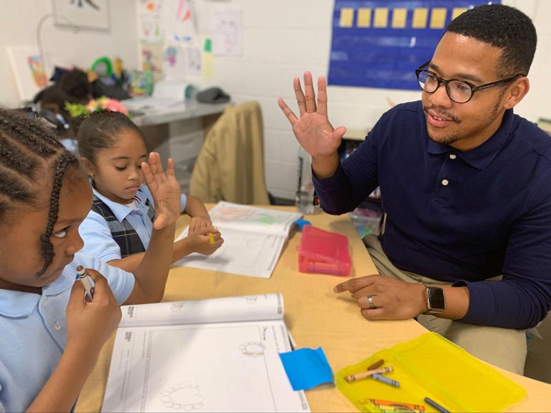 Black teacher and his students studying